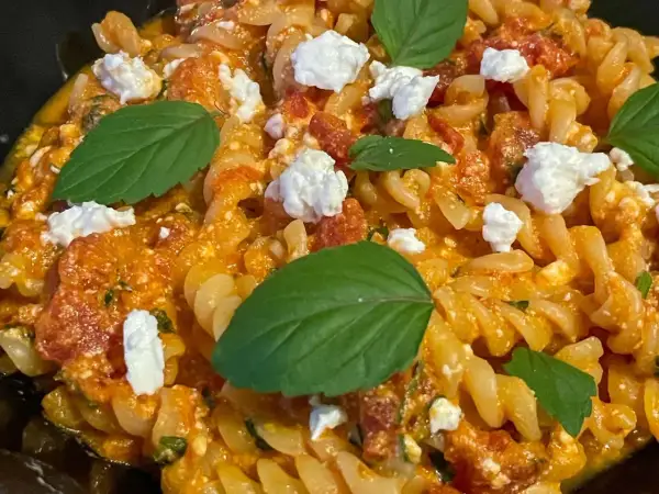 Makaron fusilli z sosem pomidorowym, kawałkami sera feta i listkami bazylii. Pyszne danie, które zachwyci każdego miłośnika pomidorów z fetą.