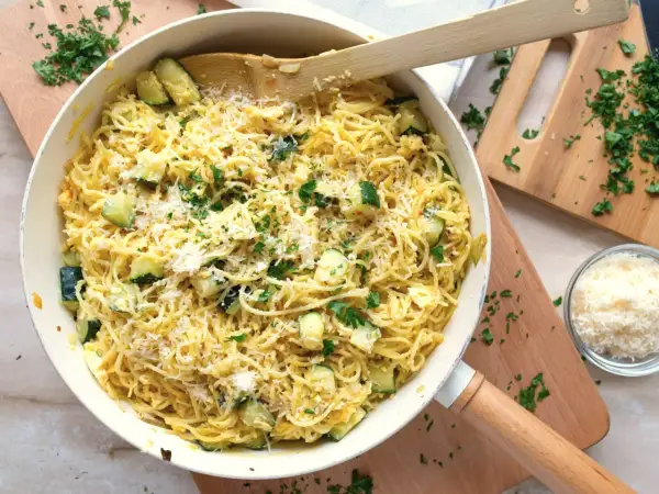 Pyszny makaron z cukinią, posypany parmezanem i świeżą natką pietruszki, gotowy do podania.