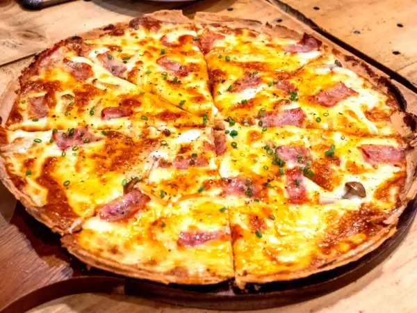 Pyszna pizza z patelni bez drożdży, z ciągnącym serem, kawałkami boczku i szczypiorkiem. Idealna na szybki obiad.