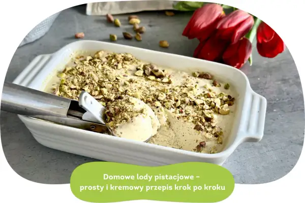 Kremowe lody pistacjowe w białej formie, posypane orzechami. Obok czerwone tulipany.